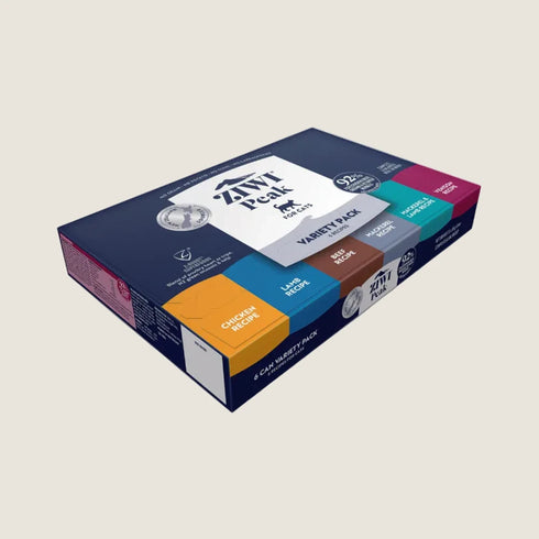 A ZIWI Peak Wet Cat Food Variety Pack, featuring six 85g cans, is displayed in a colorful box. The packaging highlights various flavors like chicken and fish, emphasizing the high meat content and premium quality ingredients.