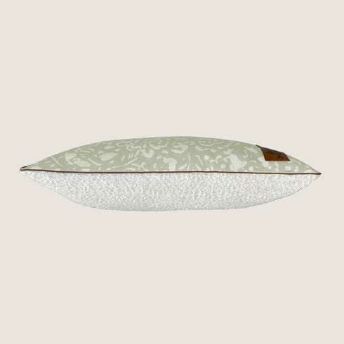 A stylish dog bed featuring a neutral green fabric with a subtle floral design on the top and a textured bouclé surface on the bottom. The bed has a sleek, elongated shape and is accented with a contrasting trim for added elegance.