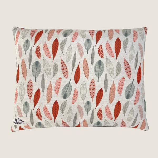 A rectangular dog bed featuring a linen-blend fabric adorned with a colorful pattern of leaves in shades of red, gray, and muted tones. The design showcases an artistic.
