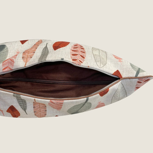 A close-up view of an open pouch featuring a light-colored fabric adorned with colorful leaf patterns in shades of rust, green, and beige. The interior of the pouch is lined with a dark brown material, showcasing a zipper closure.