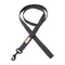 A sleek, dark gray dog lead made from soft, textured cotton lies flat against a white background. It features a matte black metal clasp and a small beige label, showcasing its minimalist and refined design.