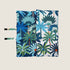 A reversible dog travel mat featuring a bold coastal design with vibrant blue, green, and orange palm tree patterns on one side and a contrasting pattern on the other. The mat is folded and secured with straps for easy transport.