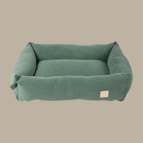 A plush, myrtle green corduroy pet bed with a rectangular shape and soft, padded sides. The bed features a simple, elegant design that blends seamlessly with home decor, offering comfort for pets.