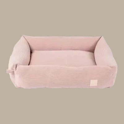 A soft blush corduroy pet bed with a rectangular shape and plush, padded edges. The bed features a removable cover for easy cleaning, showcasing a luxurious.