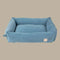A soft, rectangular dog bed in a light French blue corduroy fabric features tall, cushioned sides and a plush center. The design includes a small tag on the side, blending style and comfort for pets.